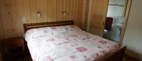 A bedroom with a wooden bed, a nightstand, and a wooden wardrobe.