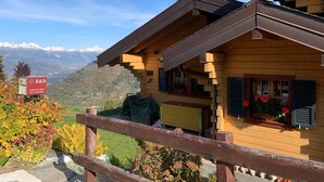 Uma cabana de madeira com varanda e vista para a paisagem montanhosa.