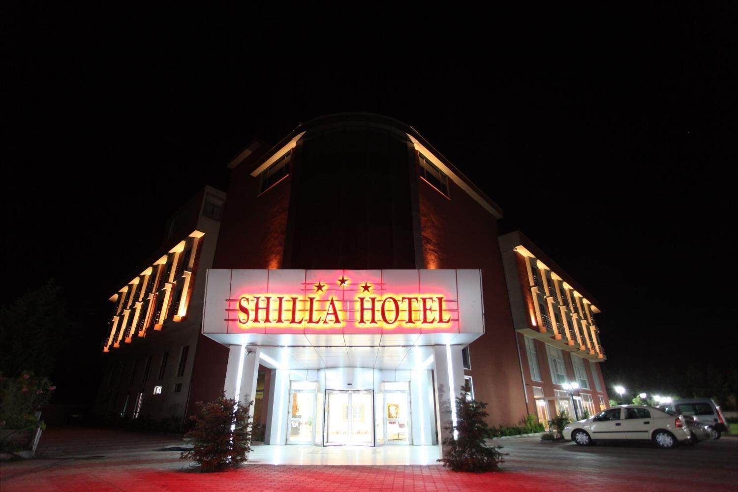 Exterior del Hotel Shilla con señalización iluminada, una entrada destacada y un área de estacionamiento.