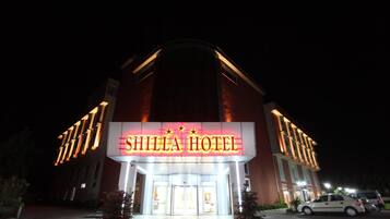 Exterior del Hotel Shilla con señalización iluminada, una entrada destacada y un área de estacionamiento.
