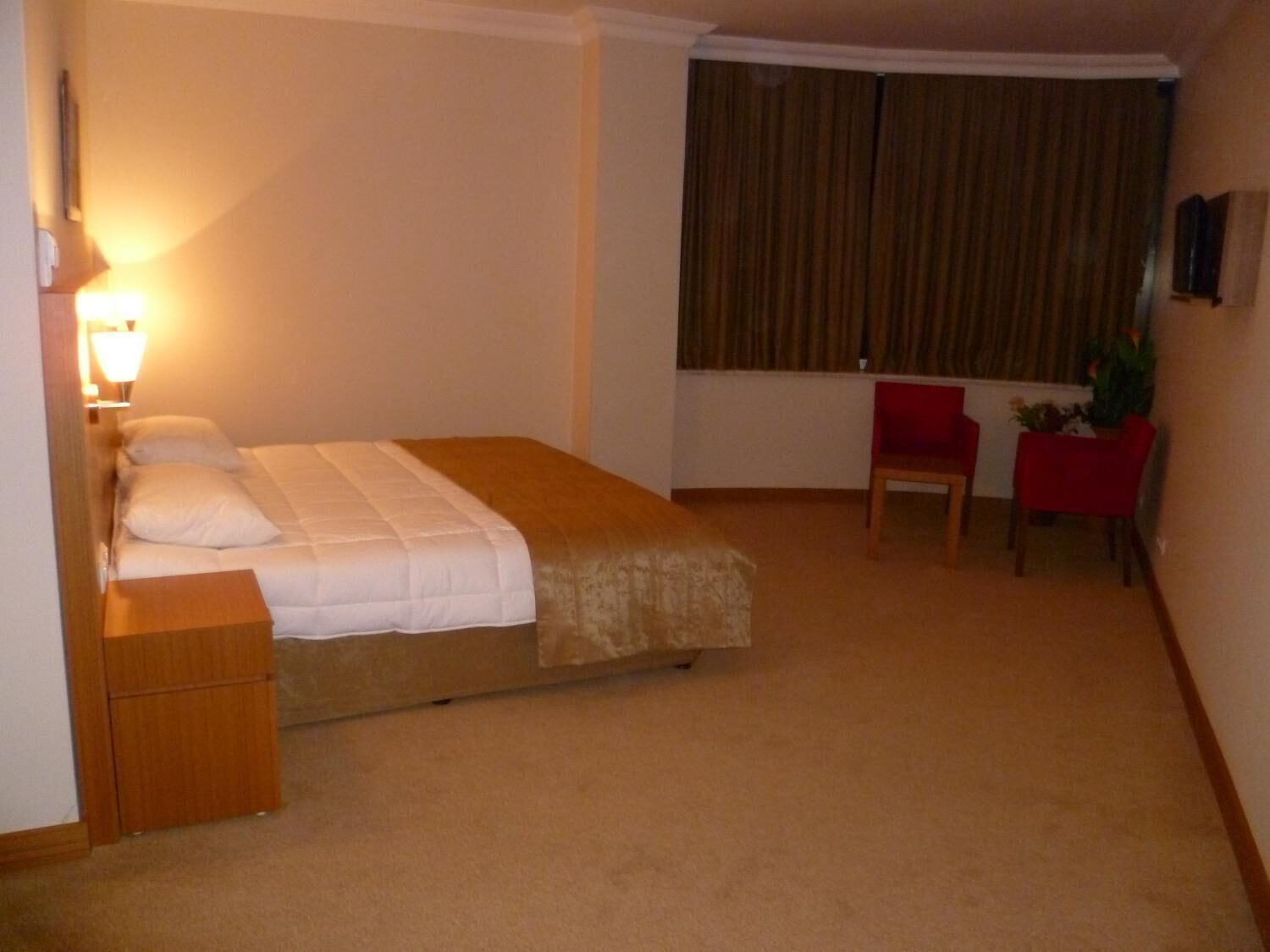 A hotel room with a bed, a desk, a chair, and a window with curtains.
