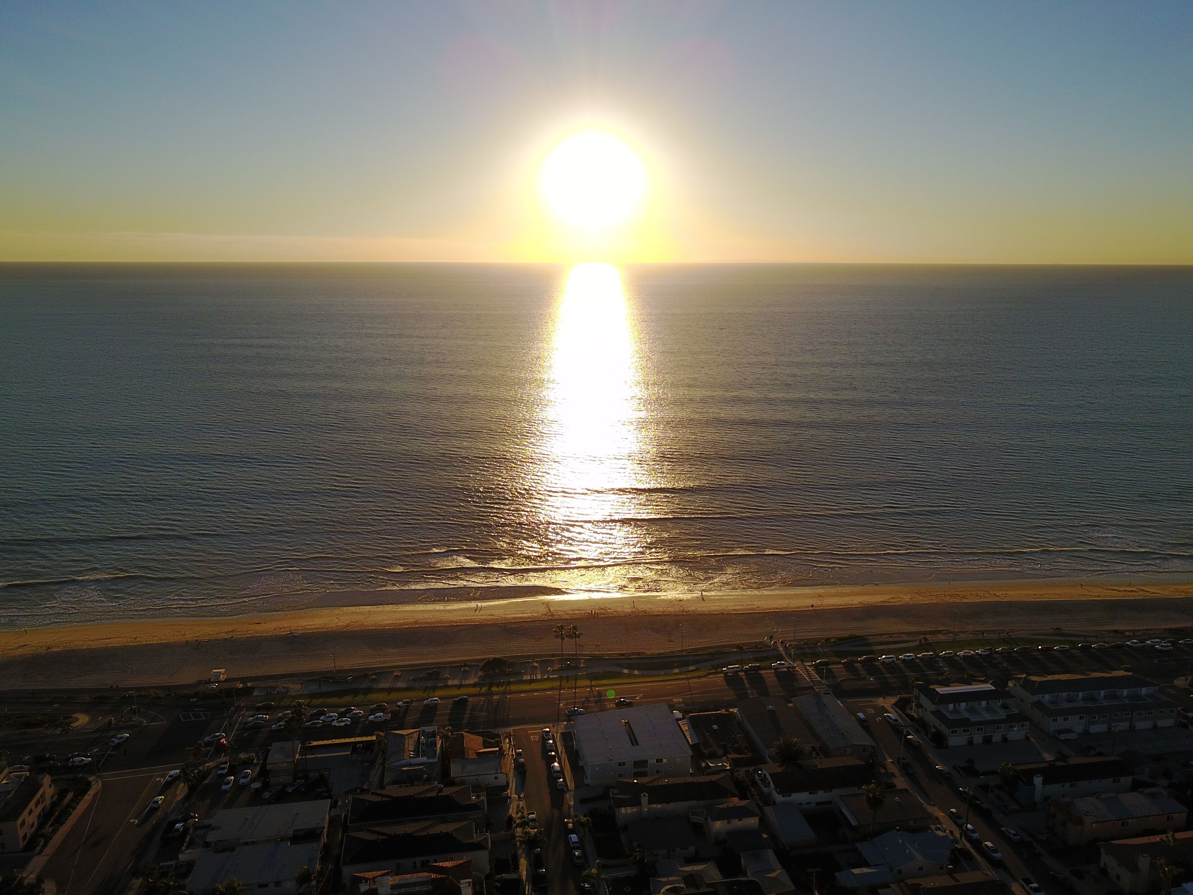 Vista aérea de una zona costera con playa y aparcamiento.