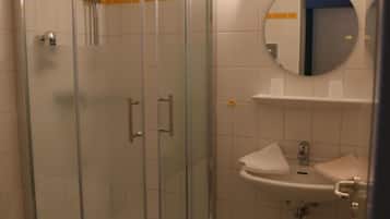 A bathroom with a glass-enclosed shower, a sink, and a toilet.