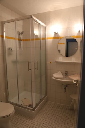 A bathroom with a glass-enclosed shower, a sink, and a toilet.