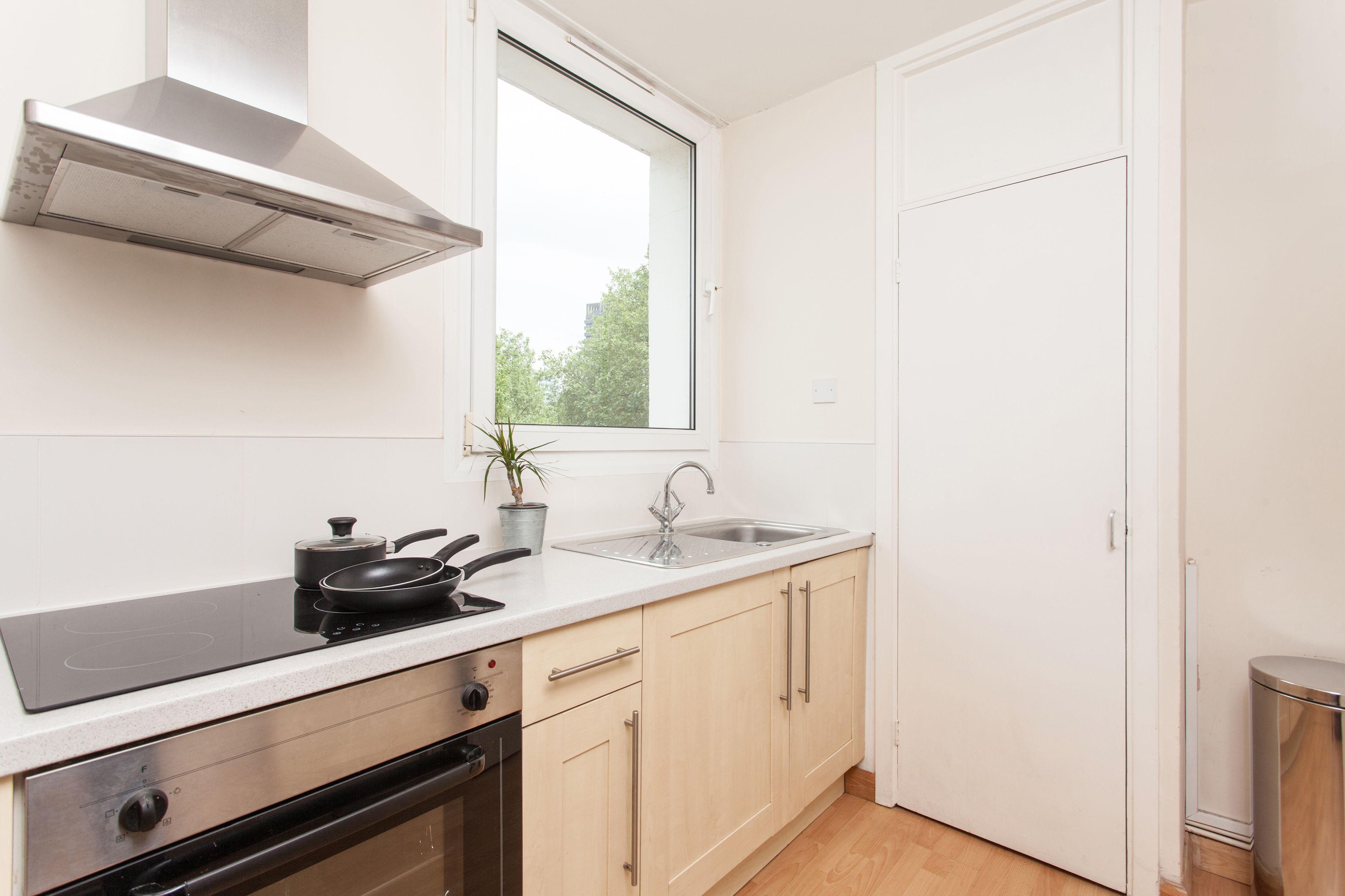 A modern kitchen with a built-in stove, a window, a sink, and a door.