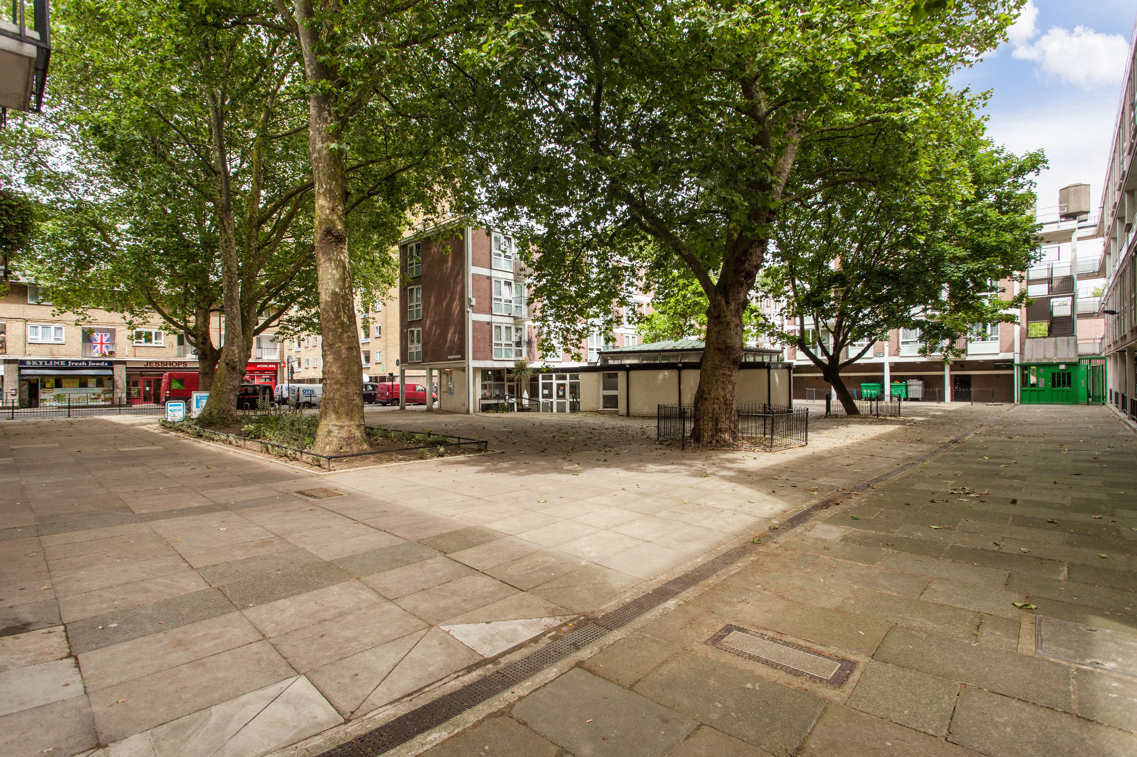 A courtyard with trees, a bench, and a building with a sign for 'Skyline Fresh Foods'.