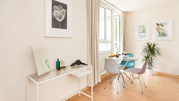 En moderne stue med et glasbord, en bærbar computer og en potteplante.