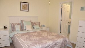 A bedroom with a large bed, a nightstand, a dresser, and a door. - Beach Across The Street! Great Views & Location! Sleeps 10 (Wildwood)