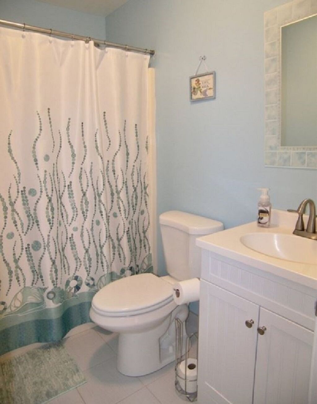 A bathroom with a toilet, sink, and shower curtain.
