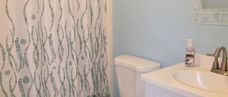 A bathroom with a toilet, sink, and shower curtain.