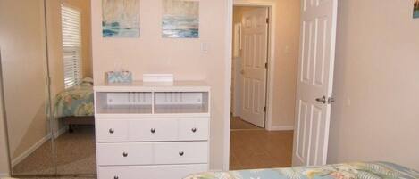 Une chambre à coucher avec un lit, une commode et deux tableaux accrochés au mur.