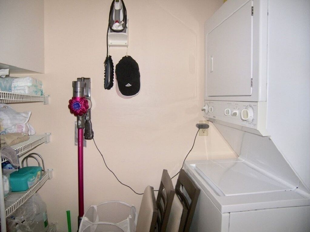 Un espace dédié à la lessive, comprenant un lave-linge, un sèche-linge, une serpillière et un aspirateur.