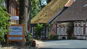 A café sign in front of a traditional building with a sloped roof. - Kulturhof (Lenzen)