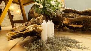 A rustic wooden table with a floral arrangement, white candles, and a large 'M' sign in the background. - Loskop Valley Lodge and Restaurant (Groblersdal)