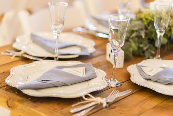 A dining table set with white plates, folded napkins, and clear glassware.