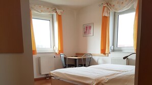 Une chambre à coucher avec un lit, un bureau, deux chaises et un radiateur.