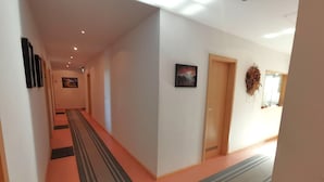 Un couloir avec un tapis à rayures, une porte en bois et un tableau encadré accroché au mur.