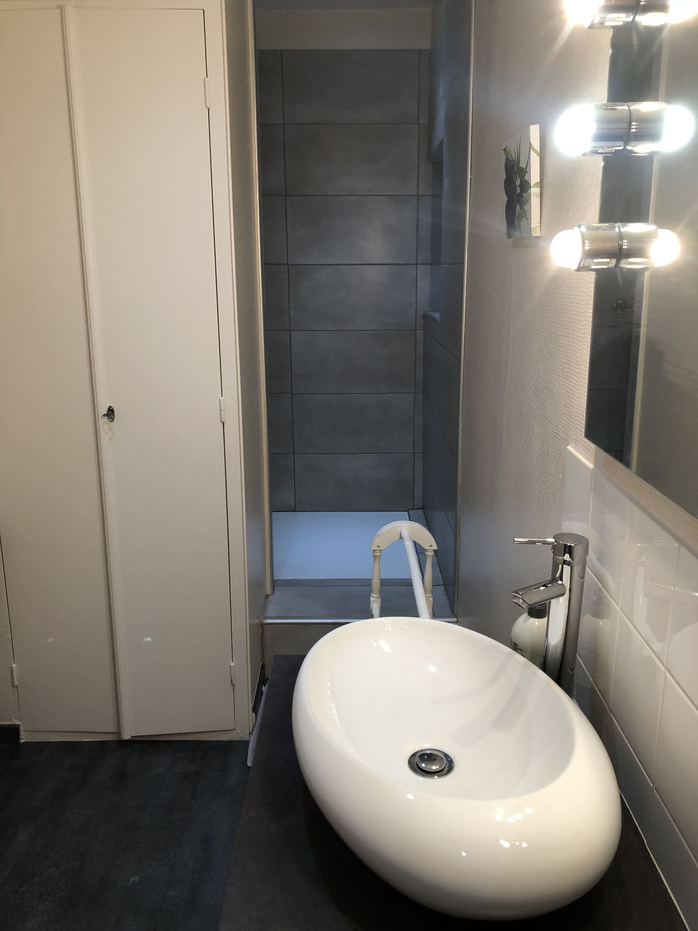 Un baño con lavamanos blanco, cabina de ducha y espejo con iluminación.