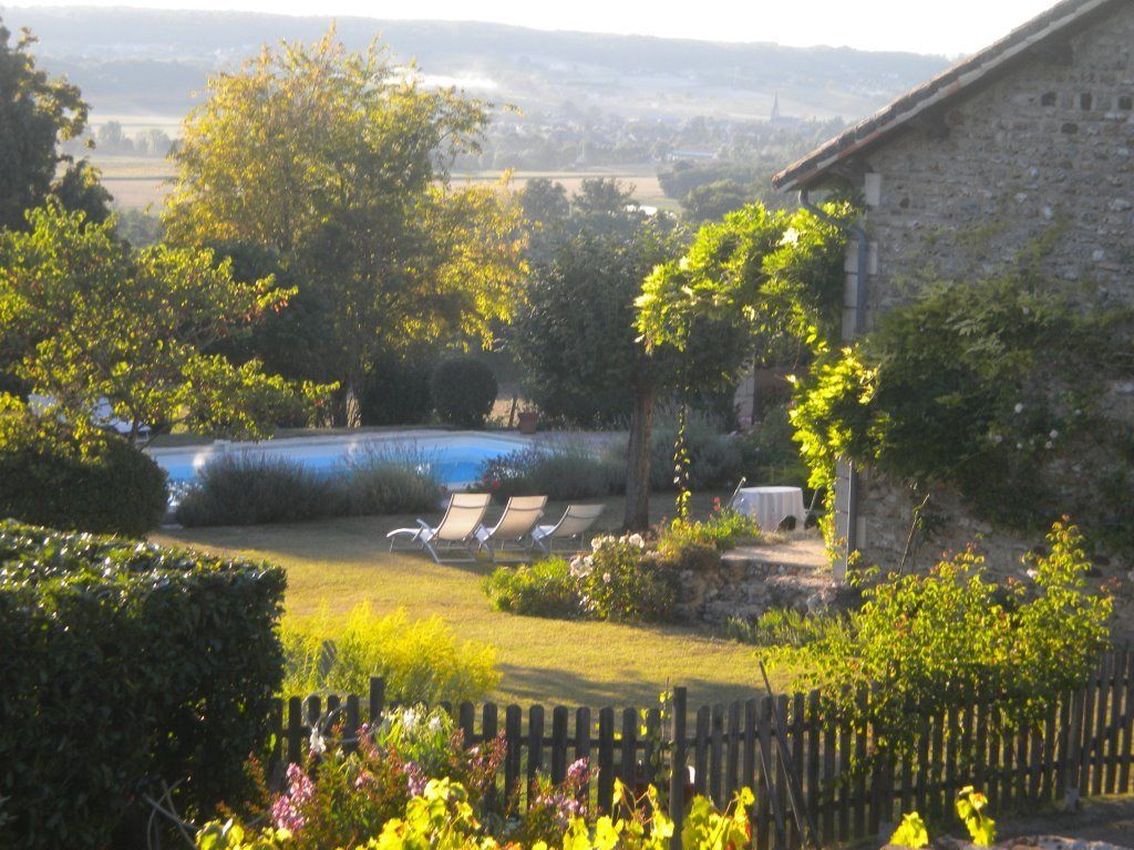 Un jardín con piscina, sillas de descanso y un edificio de piedra.
