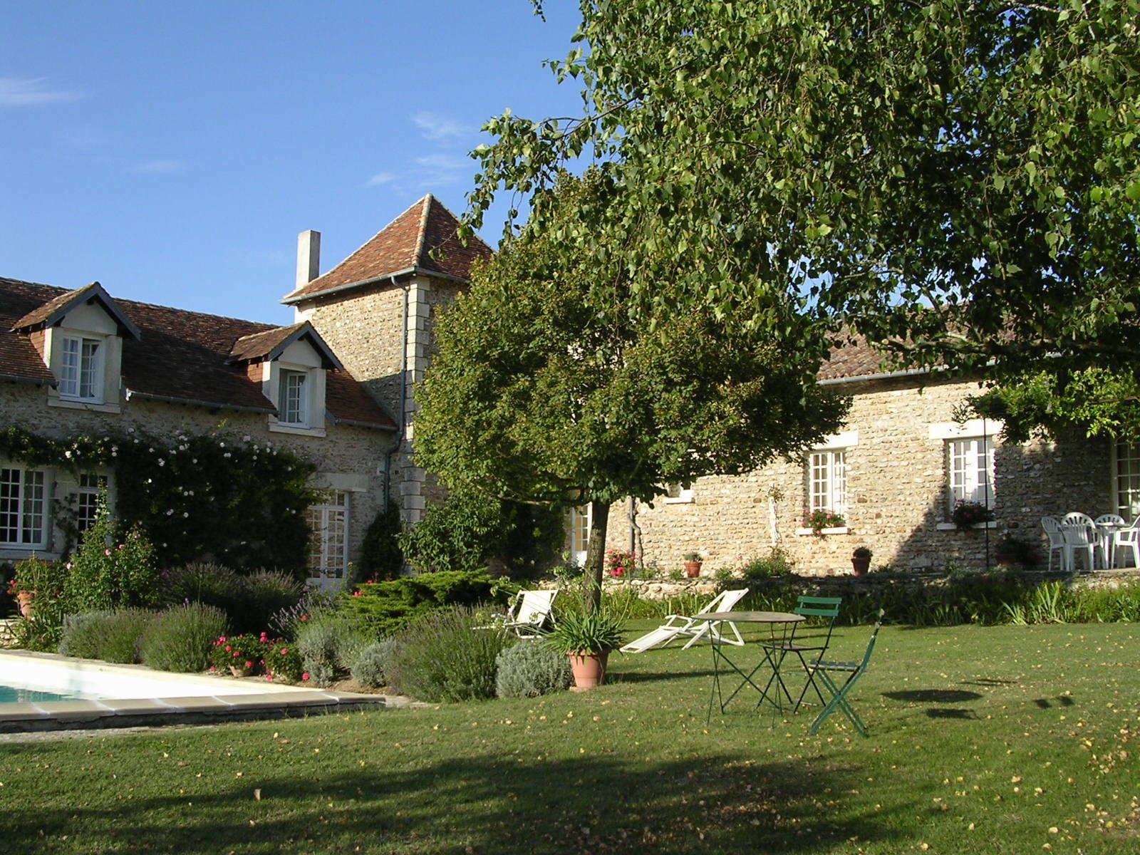 Ein Steinhaus mit Garten, Schwimmbad und Gartenmöbeln.
