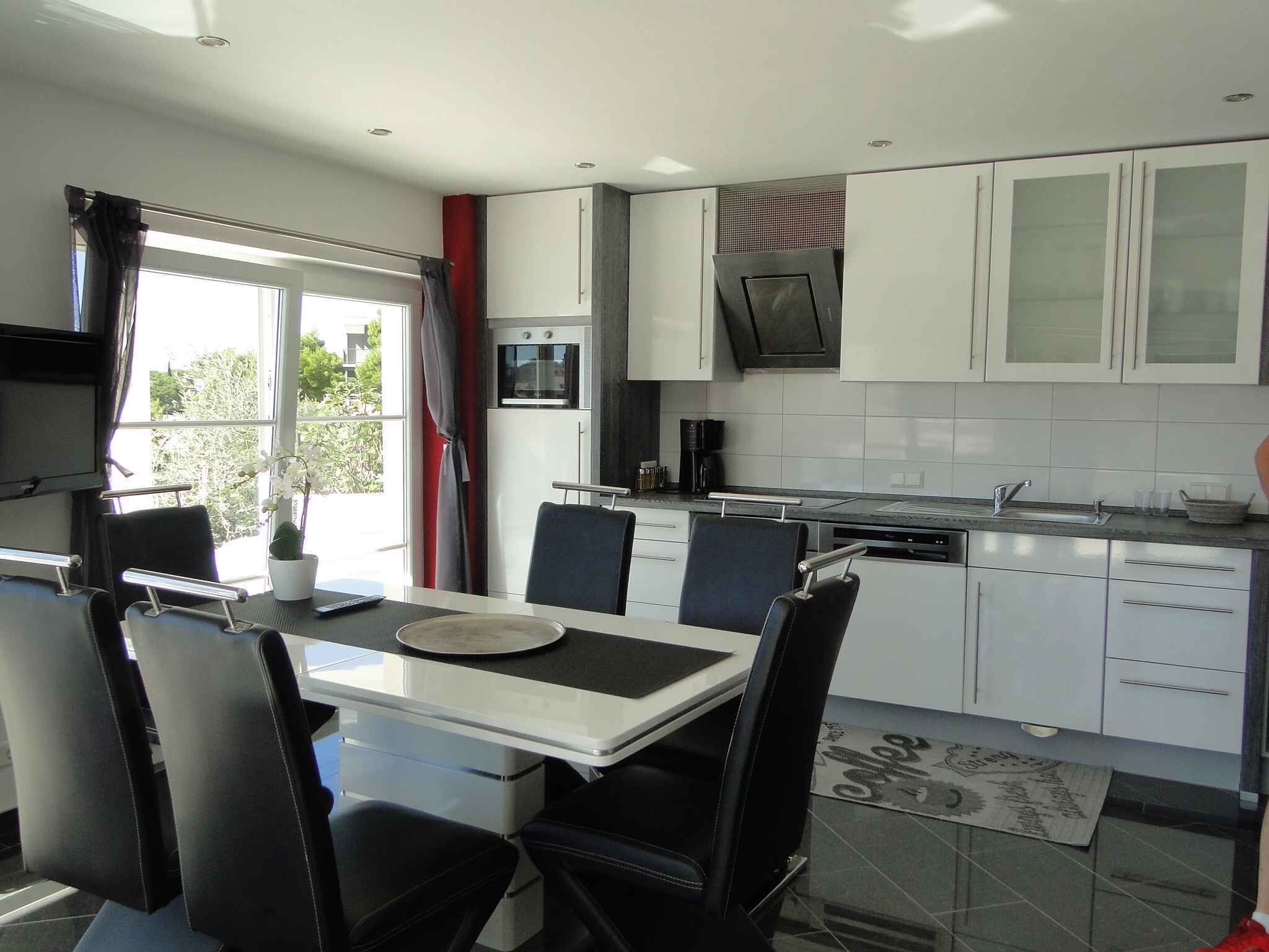 A modern kitchen with white cabinets, a black countertop, and a dining area with a table and chairs.