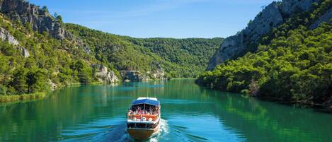 Un bateau sur une rivière, entouré de collines verdoyantes.