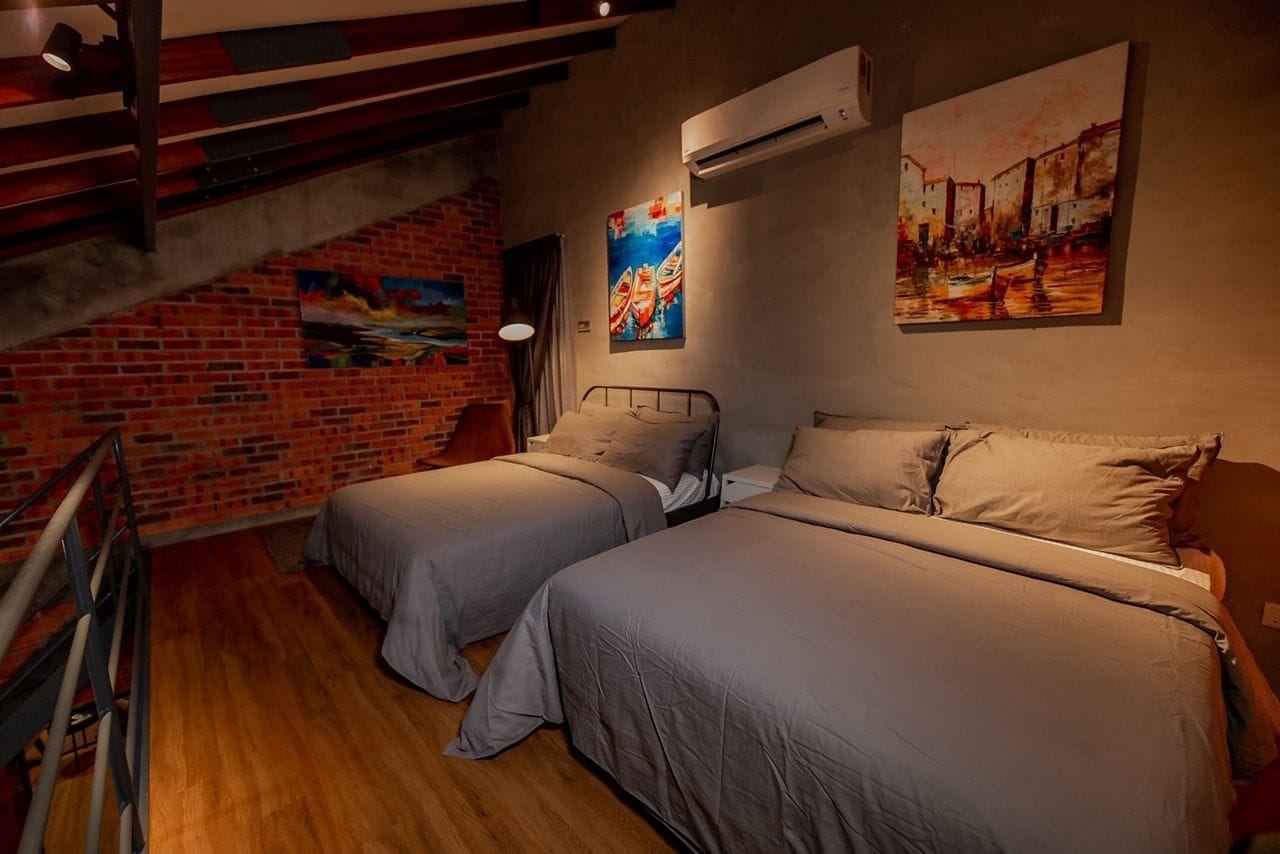 Ein Zimmer mit zwei Betten, einer Ziegelwand und Kunstwerken an den Wänden.