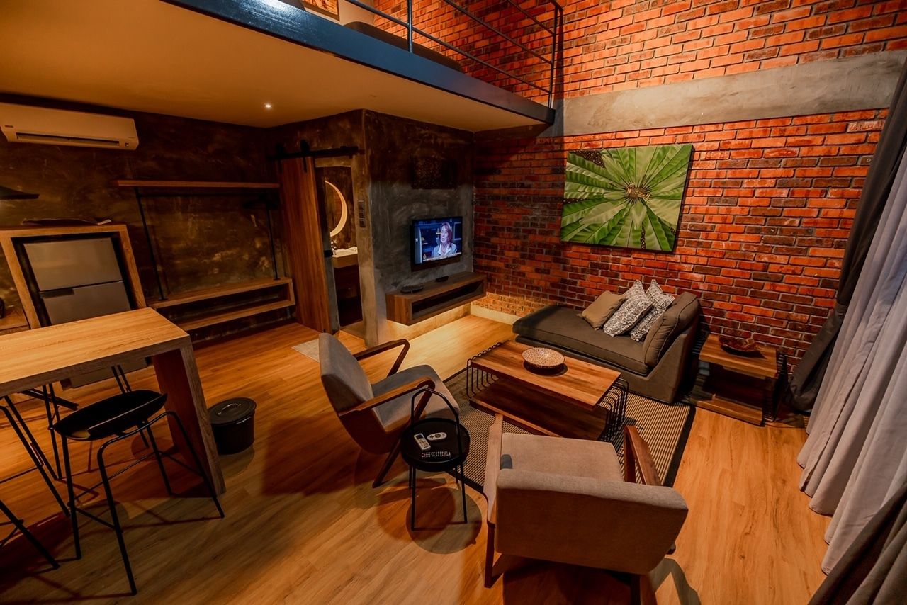 A cozy living room with a brick wall, a television, a sofa, and a dining area with a table and chairs.