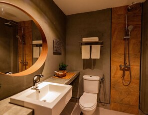 A modern bathroom with a large mirror, a sink, a toilet, and a shower.