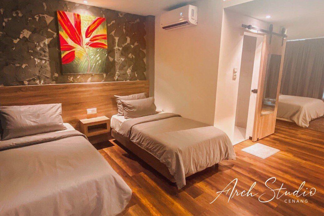 A hotel room with two beds, a wooden floor, a large floral artwork on the wall, and an air conditioning unit.