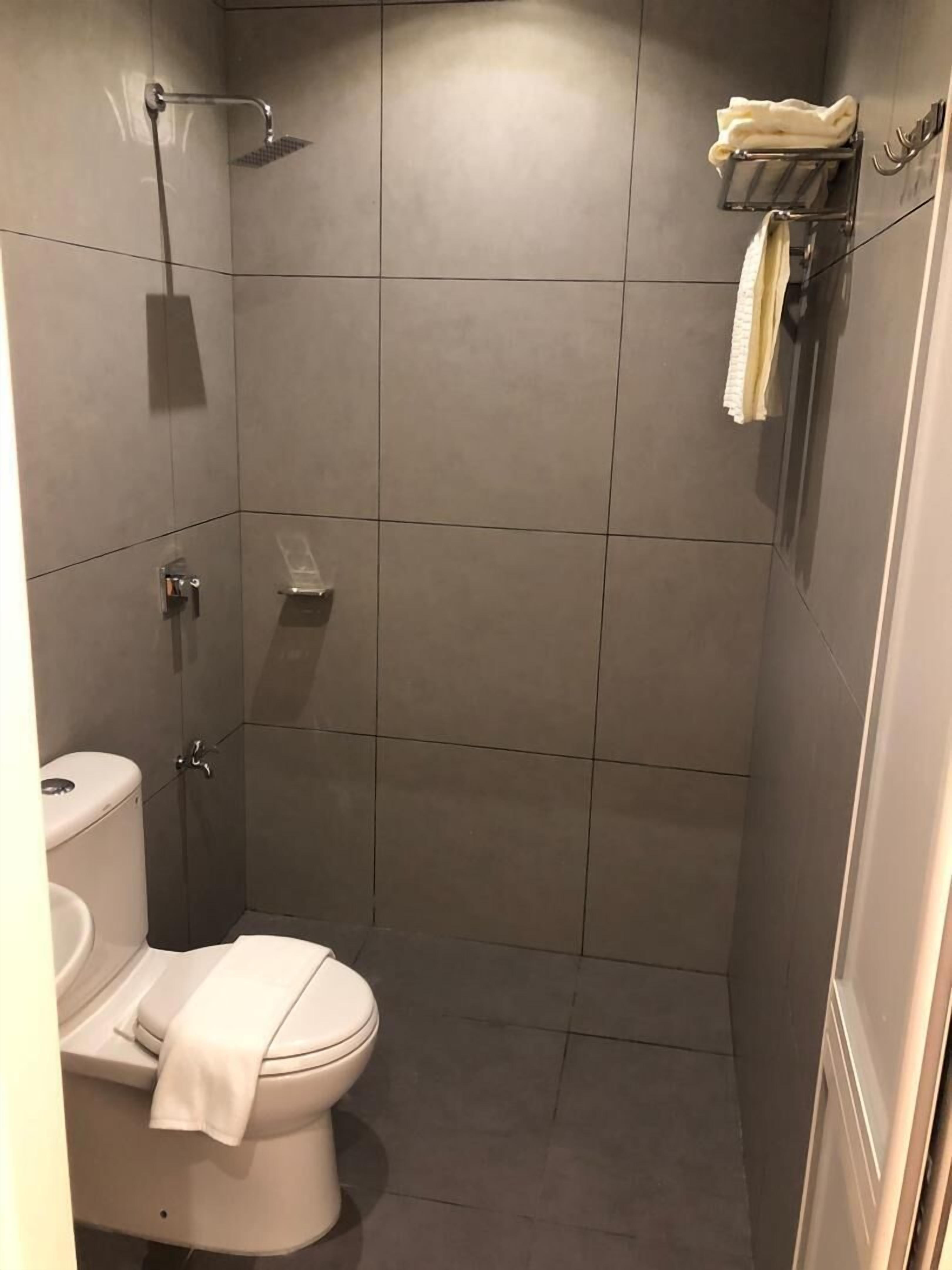 A small, modern bathroom with a toilet, a shower, and a towel rack.