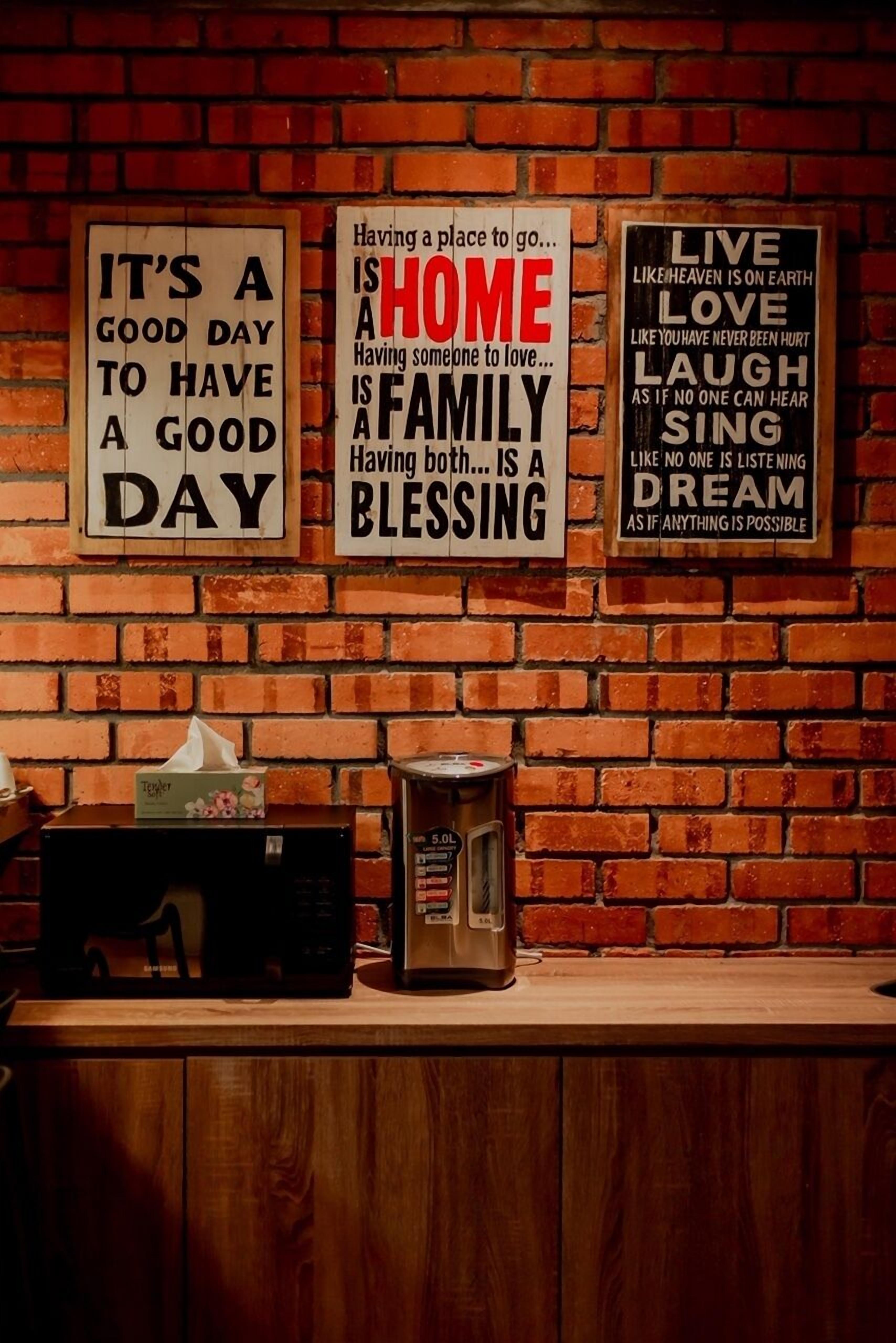 A brick wall with motivational signs and a microwave on a wooden counter.