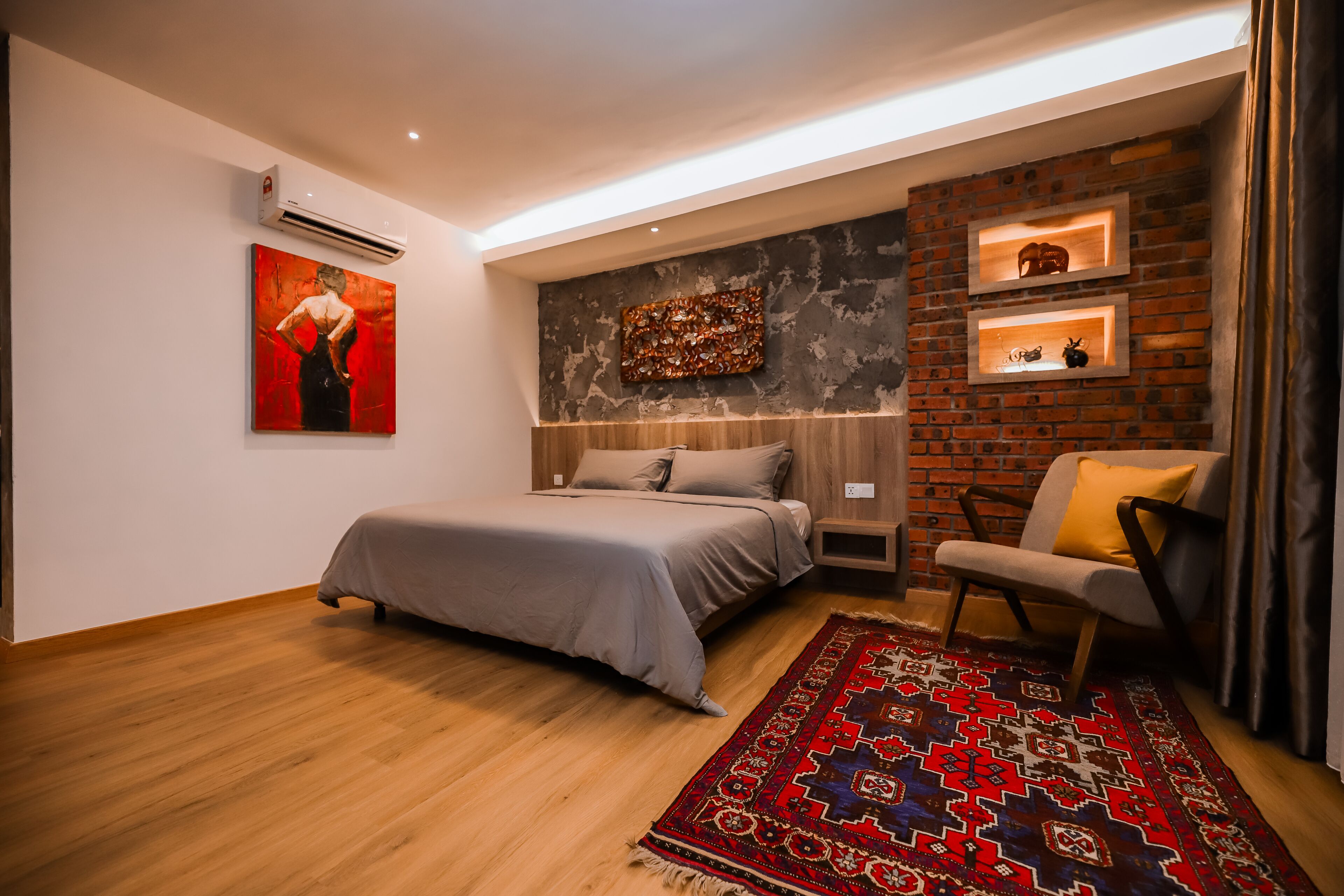 A modern bedroom with a bed, a chair, a rug, and decorative shelves.