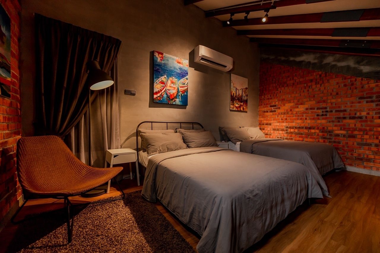 Une chambre avec un mur en briques, deux lits, une chaise et des œuvres d’art.