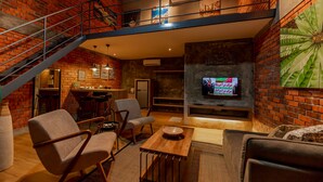 A spacious living area with a brick wall, a wooden coffee table, and comfortable seating. - Arch Studio Cenang (Langkawi)