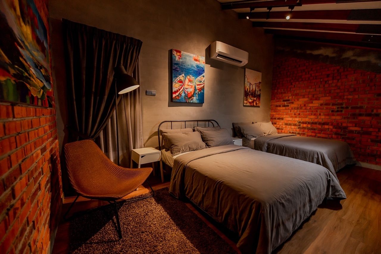 Une chambre avec deux lits, une chaise et des œuvres d’art accrochées aux murs.