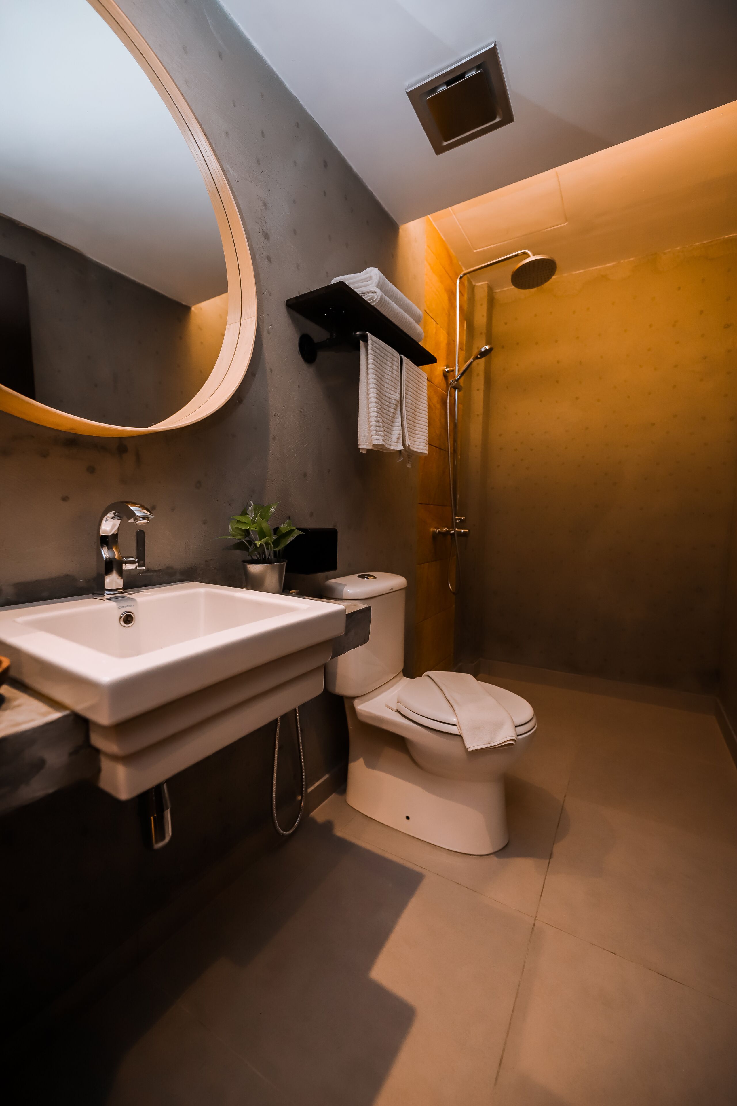 A modern bathroom with a large mirror, a sink, a toilet, and a shower.