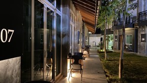 A modern building with glass doors, numbered 07, and a covered outdoor seating area with chairs and tables. - Arch Studio Cenang (Langkawi)