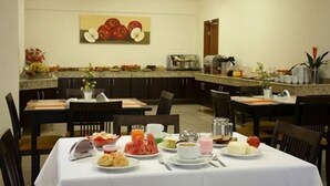 A breakfast setting with a table set for two, featuring a variety of dishes including pastries, fruit, and beverages. - Serema Palace Hotel (Lavras)