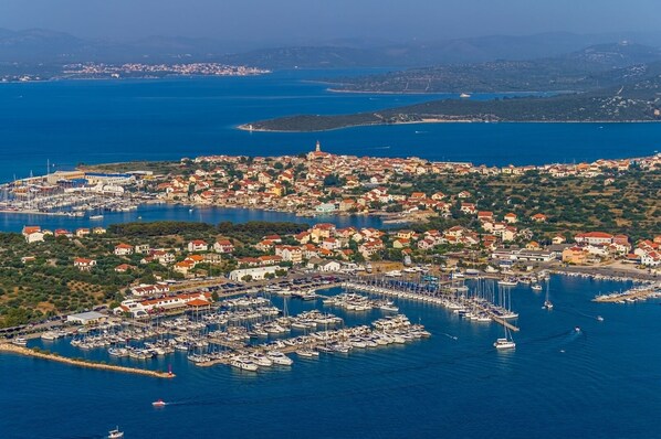 An aerial view of a coastal town with a marina filled with boats, surrounded by residential buildings and a prominent church.