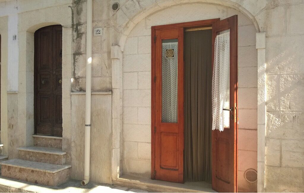 Um edifício com porta de madeira e janela com cortina de renda.