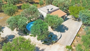 An aerial view of a property with a swimming pool, a small building, and surrounding trees. - Casale Valle degli Ulivi (Ostuni)