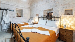 A room with two beds, a wooden nightstand, a wall-mounted shelf, and a towel rack. - Casale Valle degli Ulivi (Ostuni)