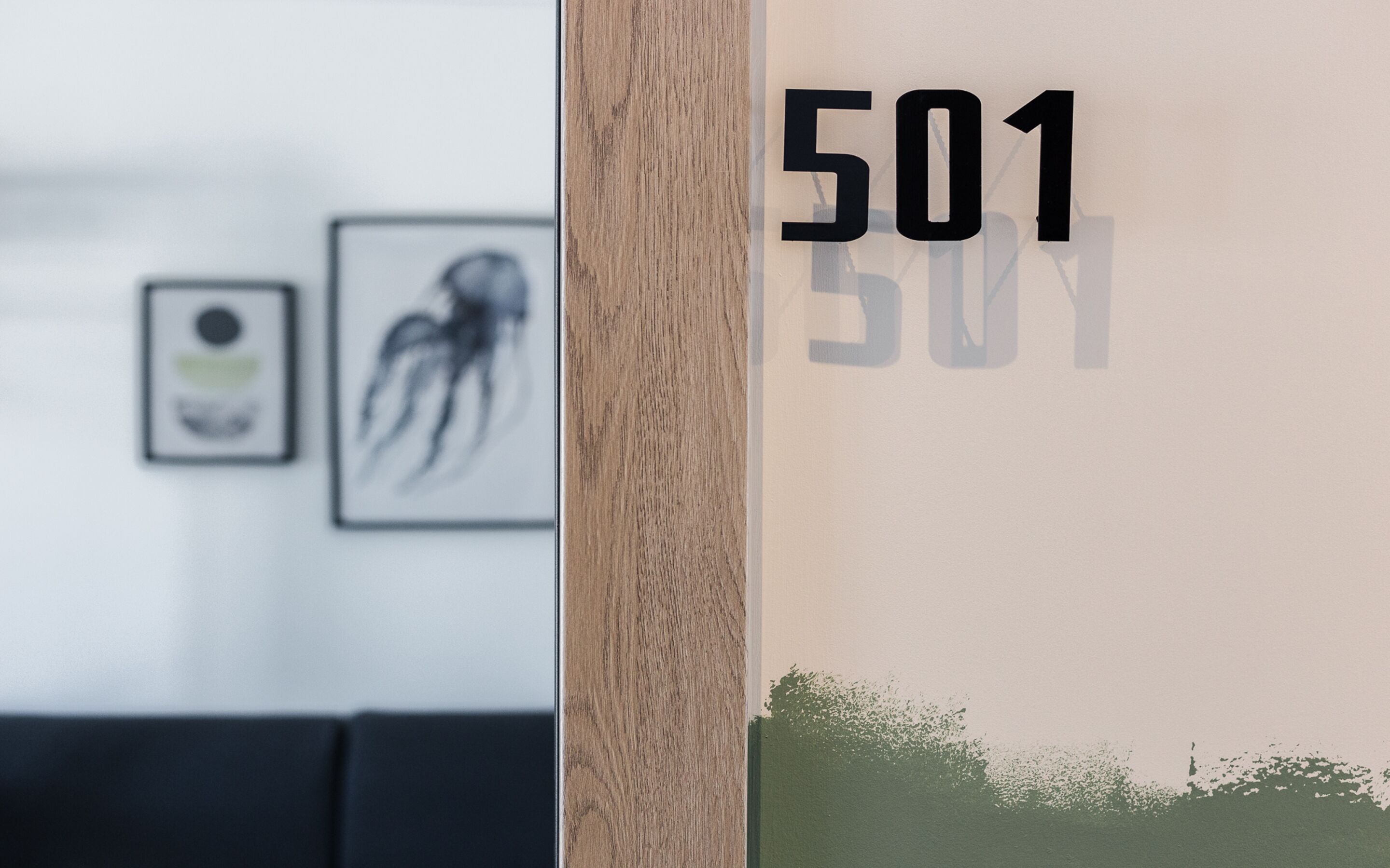 Una pared con el número 501, una partición de madera y dos cuadros enmarcados.