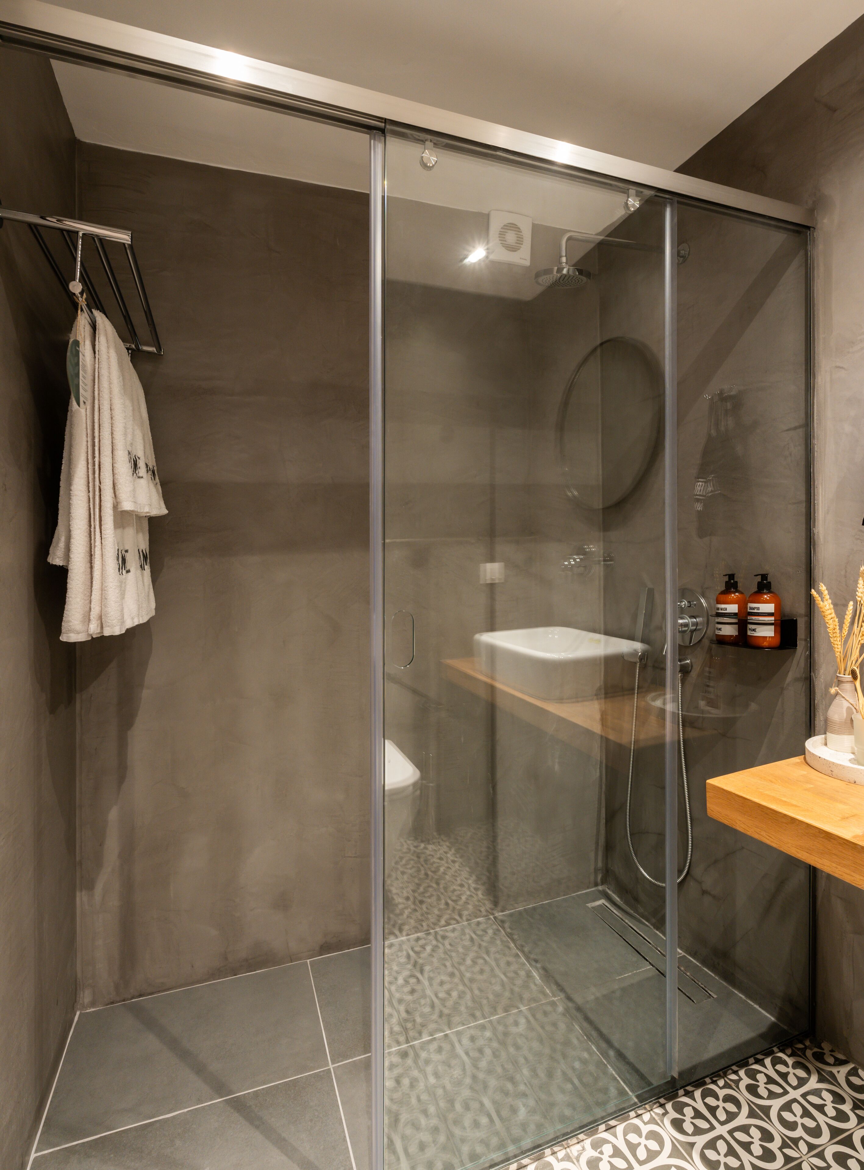 A modern bathroom with a glass-enclosed shower, a white sink, and a wooden vanity.