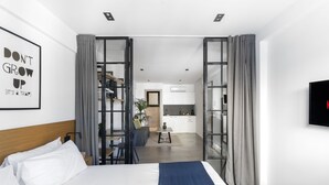 A modern hotel room with a large bed, a desk, and a kitchenette. - Pame House (Athens)