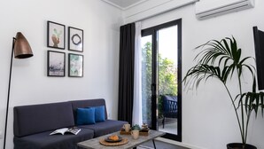 A modern living room with a dark grey sofa, a coffee table, and a potted plant. - Pame House (Athens)