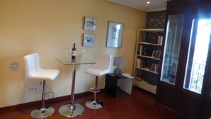 A modern living room with a glass table, two white chairs, a bookshelf, and a window. - Hotel Los Arcos (Ainsa)