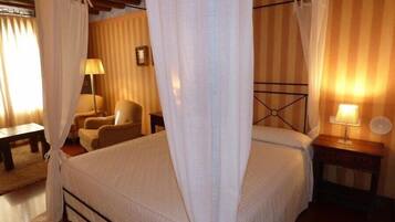 A bedroom with a bed, a chair, a bedside table, and a lamp.