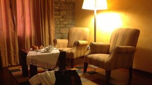 A cozy room with two armchairs, a small table with a teapot and cups, a lamp, and a suitcase on the floor. - Hotel Los Arcos (Ainsa)